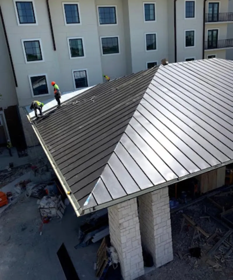 Crew installing standing seam metal roof panels on a commercial project in Hastings